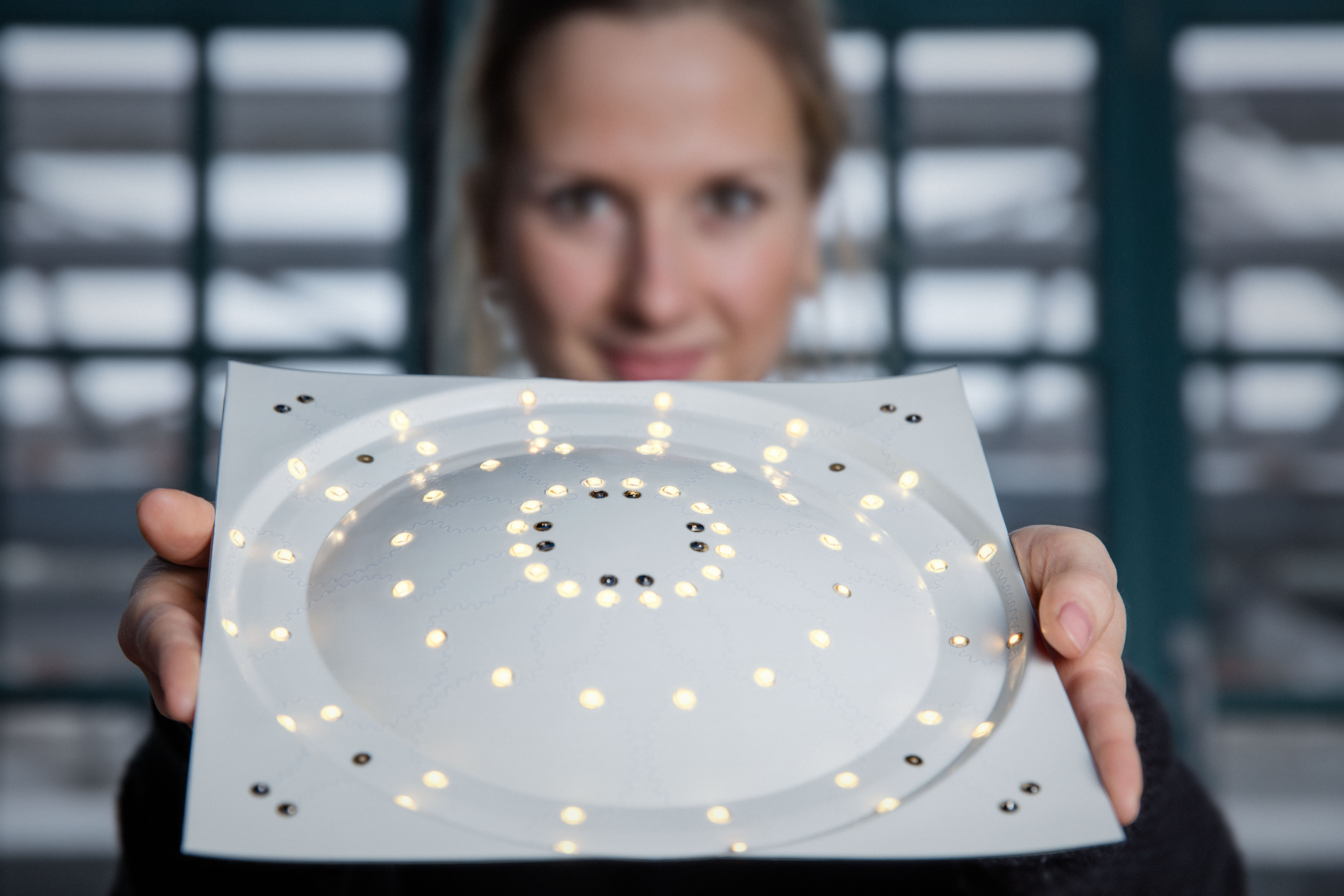 Person holding a square plate featuring circularly arranged glowing LEDs