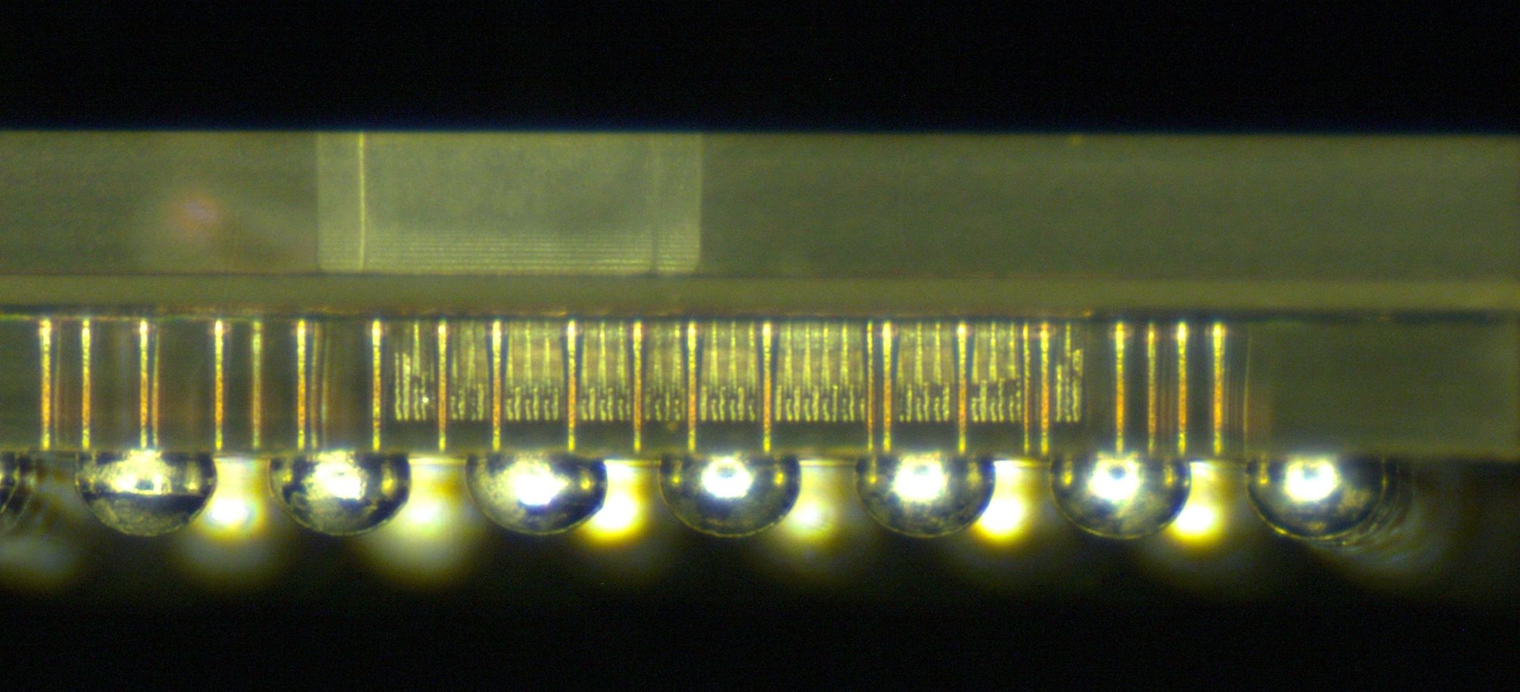 The side view of the glass package shows its three-layered structure, vias, and solder balls.