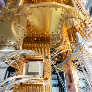 Detailaufnahme eines Quantencomputers mit goldenen Komponenten und zahlreichen Kabeln. / Detailaufnahme eines Quantencomputers mit goldenen Komponenten und zahlreichen Kabeln.
